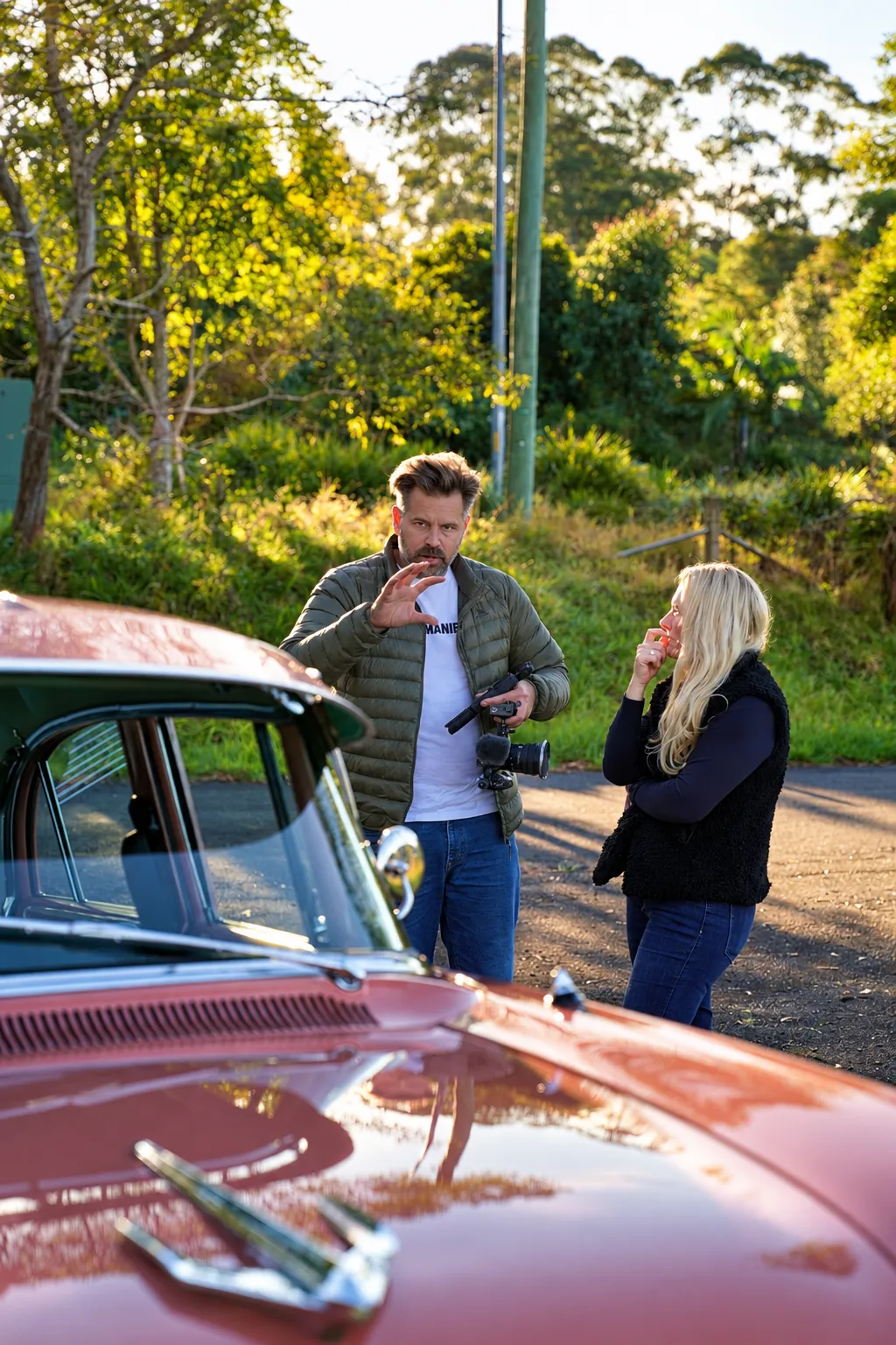Content lead filming with a team member beside a vintage car